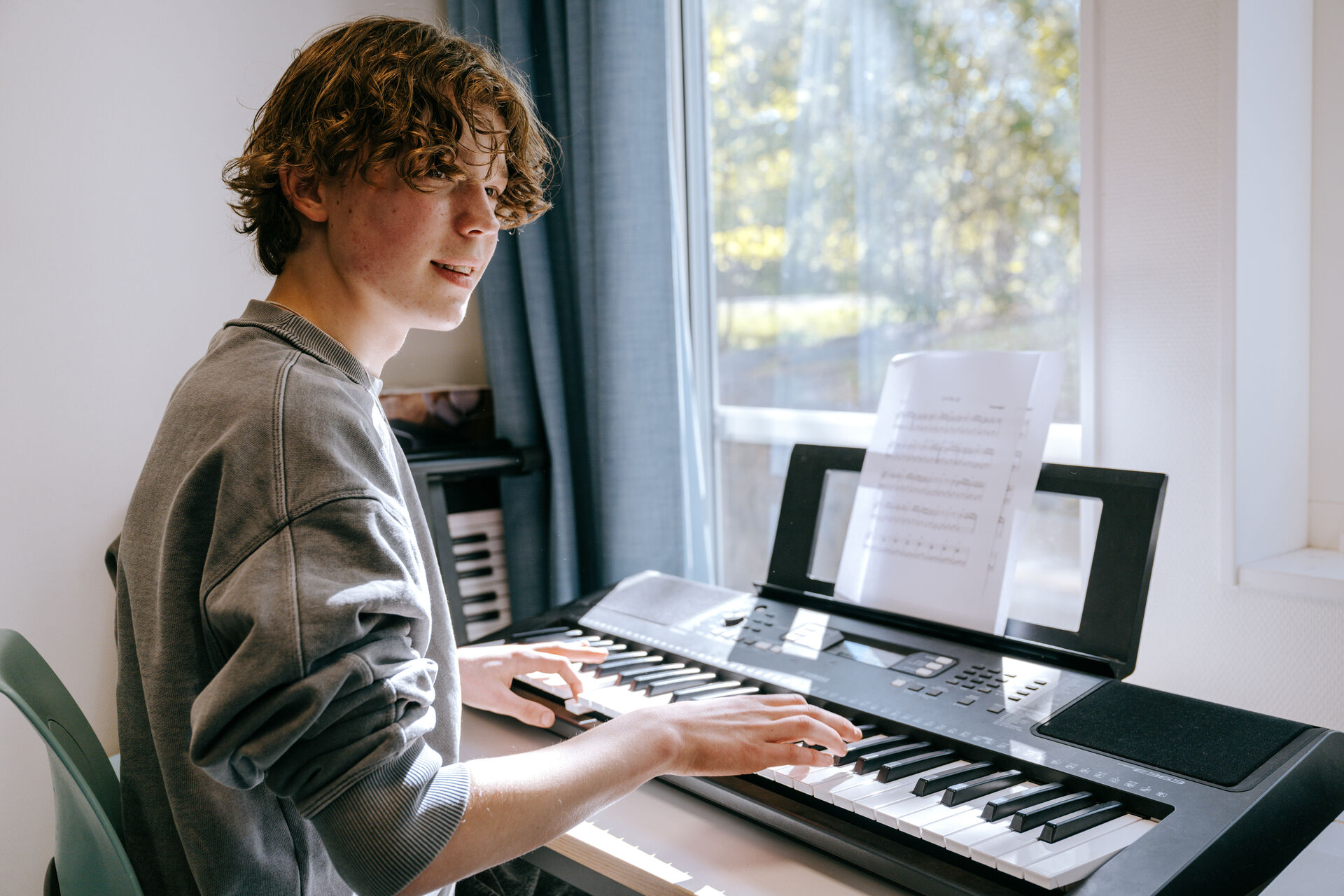En elev spelar piano i ett musikrum i Expandias modullösning på Ekens skola i Hammarby Sjöstad, där dagsljus från stora fönster skapar en lugn och inspirerande lärmiljö.