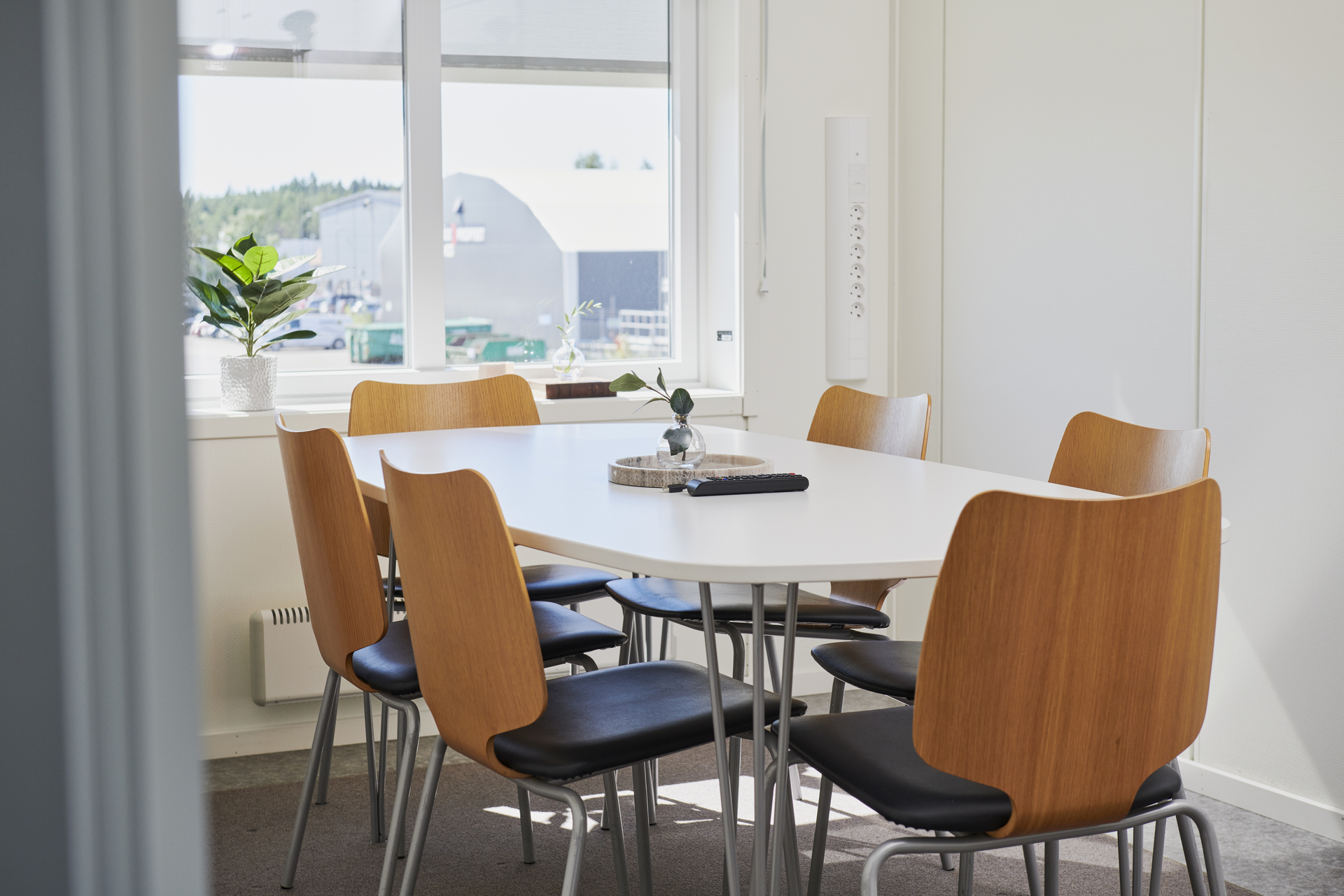 Mindre mötesrum i kontorsmoduler från Expandia med ovalt bord, trästolar och plats för flera personer. Rummet är ljust med fönster, växter och enkel inredning för möten. Bilden är tagen i kontorsmoduler vid Alviks trafik i Luleå.