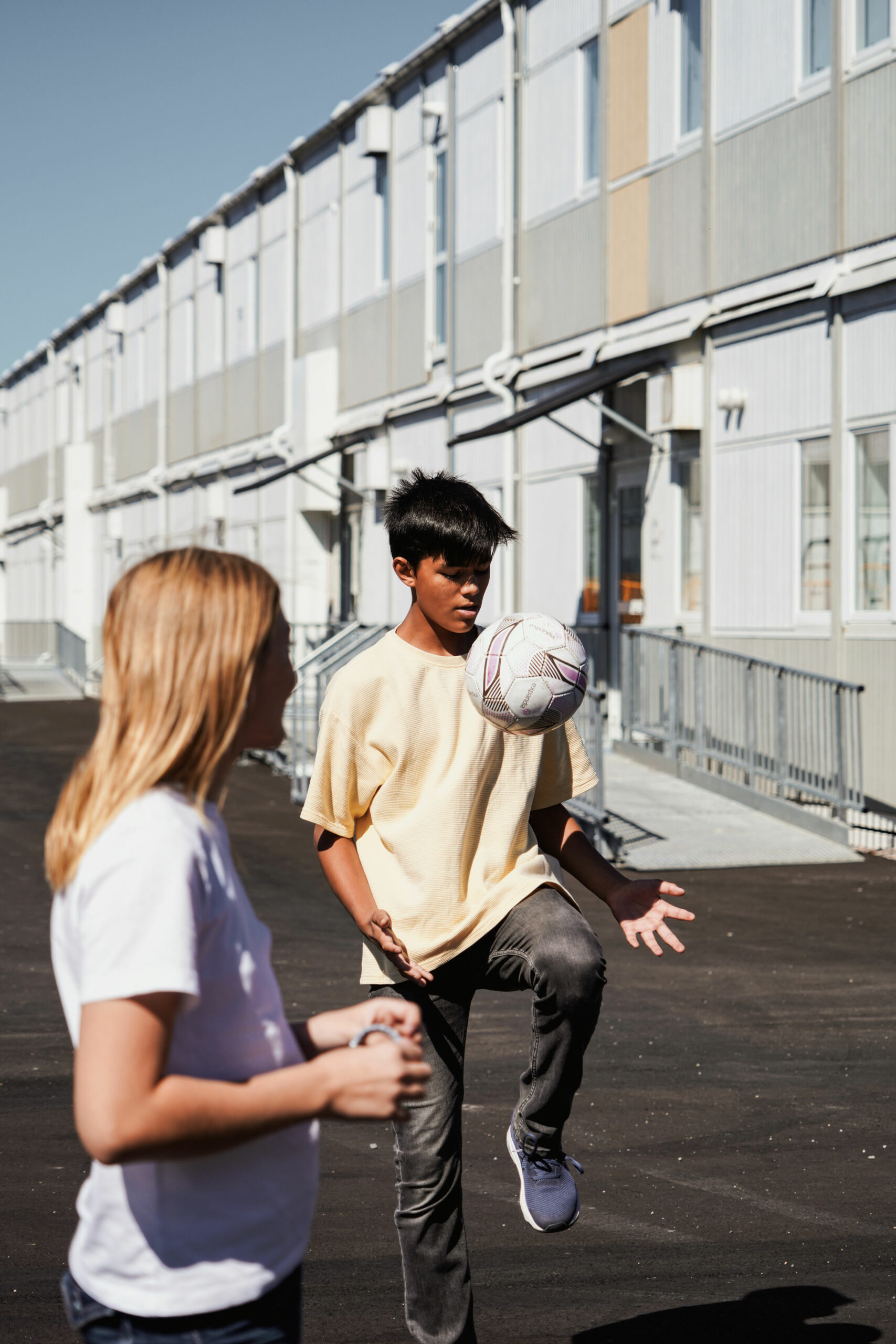 Elever leker på skolgård vid Nyckelbergsskolan i Köping med skolmoduler från Expandia i bakgrunden, trygg och aktiv utemiljö för skolverksamhet.