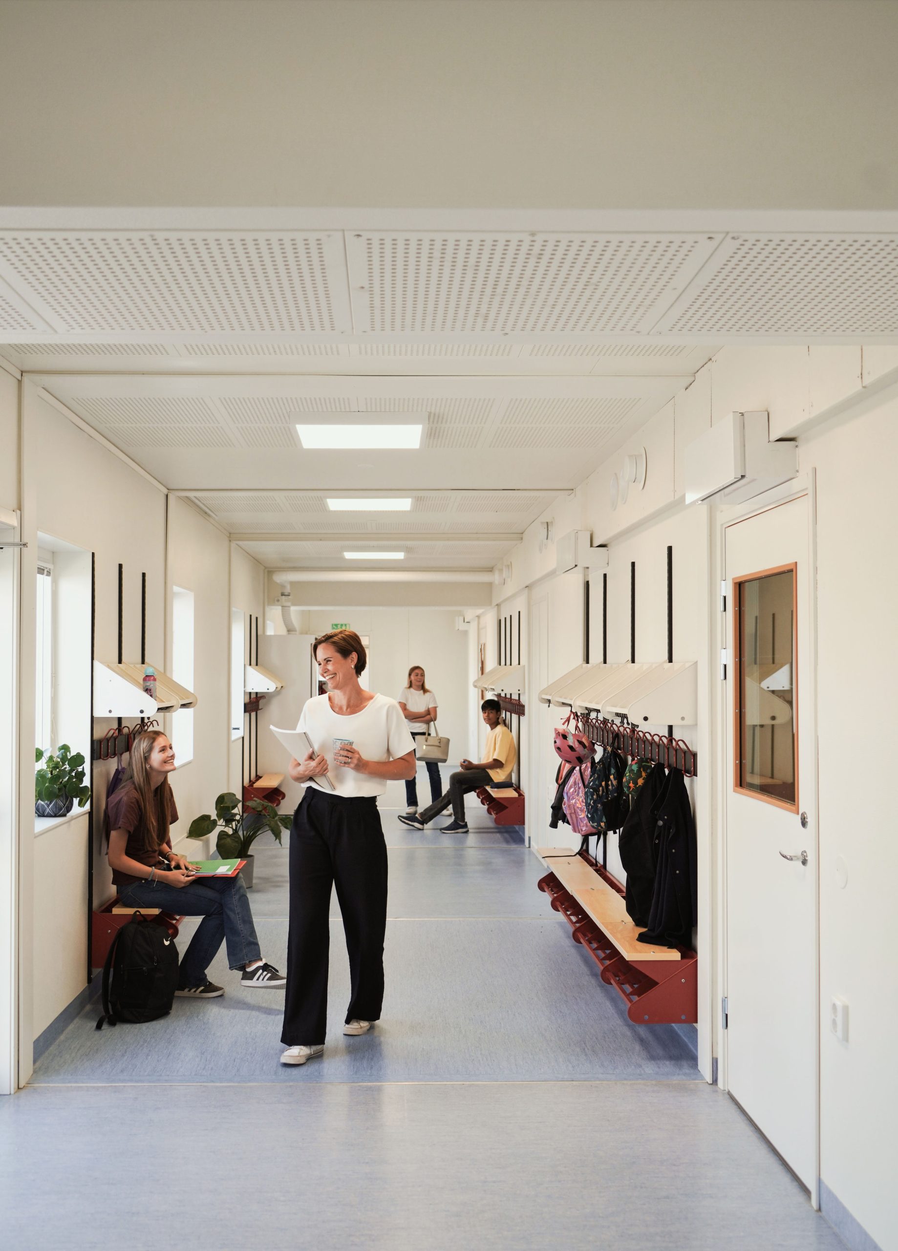 Vardagsmiljö i skolmoduler vid Nyckelbergsskolan i Köping där elever och personal vistas i ljus och funktionell korridor anpassad för skolverksamhet.