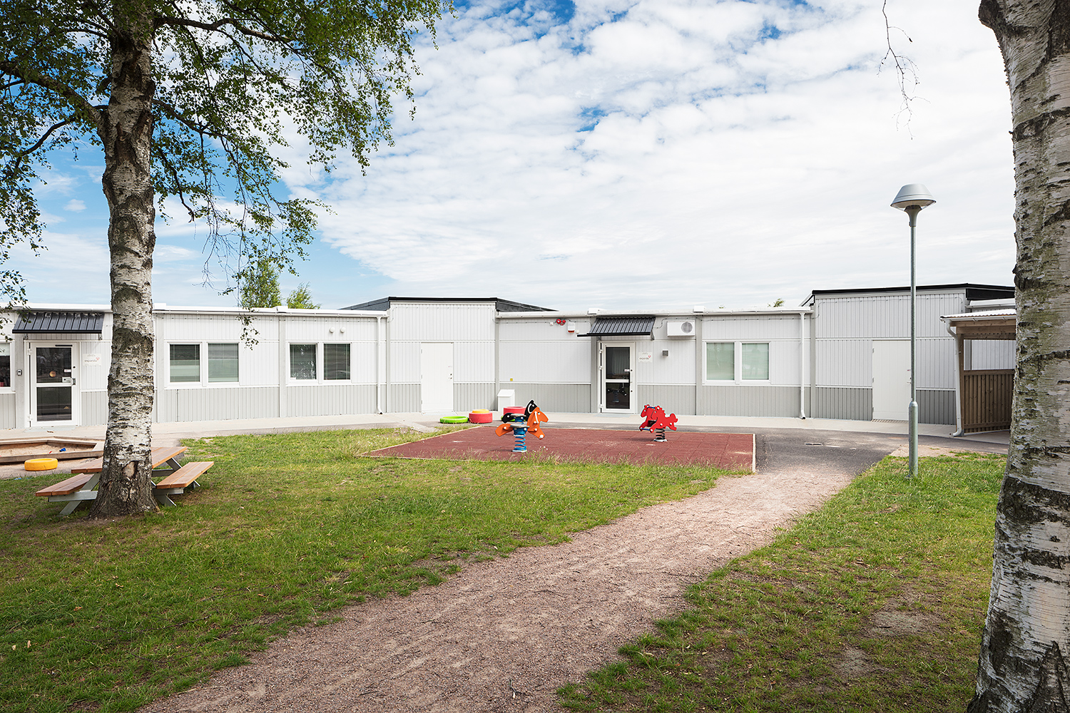 Nordala förskola i Vallås, expandias moduler, grå och vit fasad, träd och gröntområde, lekpark