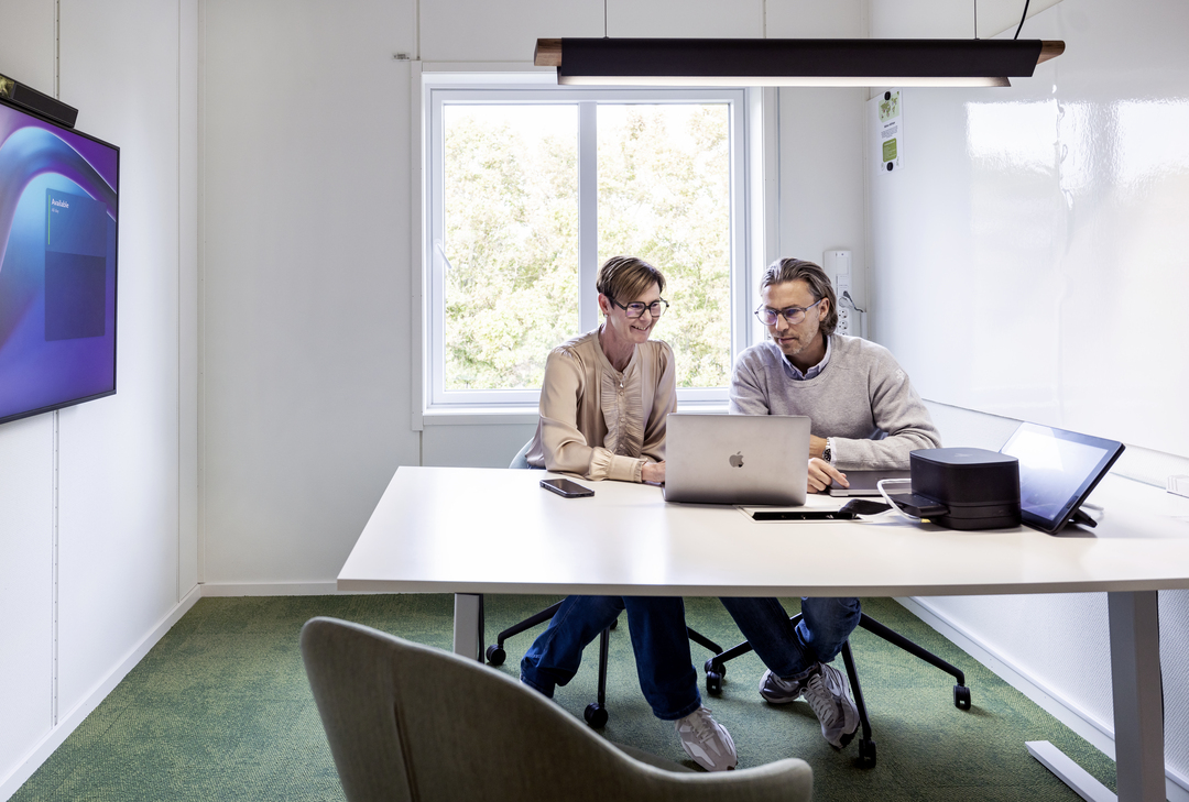 Mötes- och arbetsrum i kontorsmoduler hos Polypeptide med medarbetare som samarbetar vid bord och datorer, utrustade med skärmar, whiteboard, glaspartier, grön heltäckningsmatta och modern belysning i en ljus och funktionell kontorsmiljö – kontorsmoduler från Expandia.