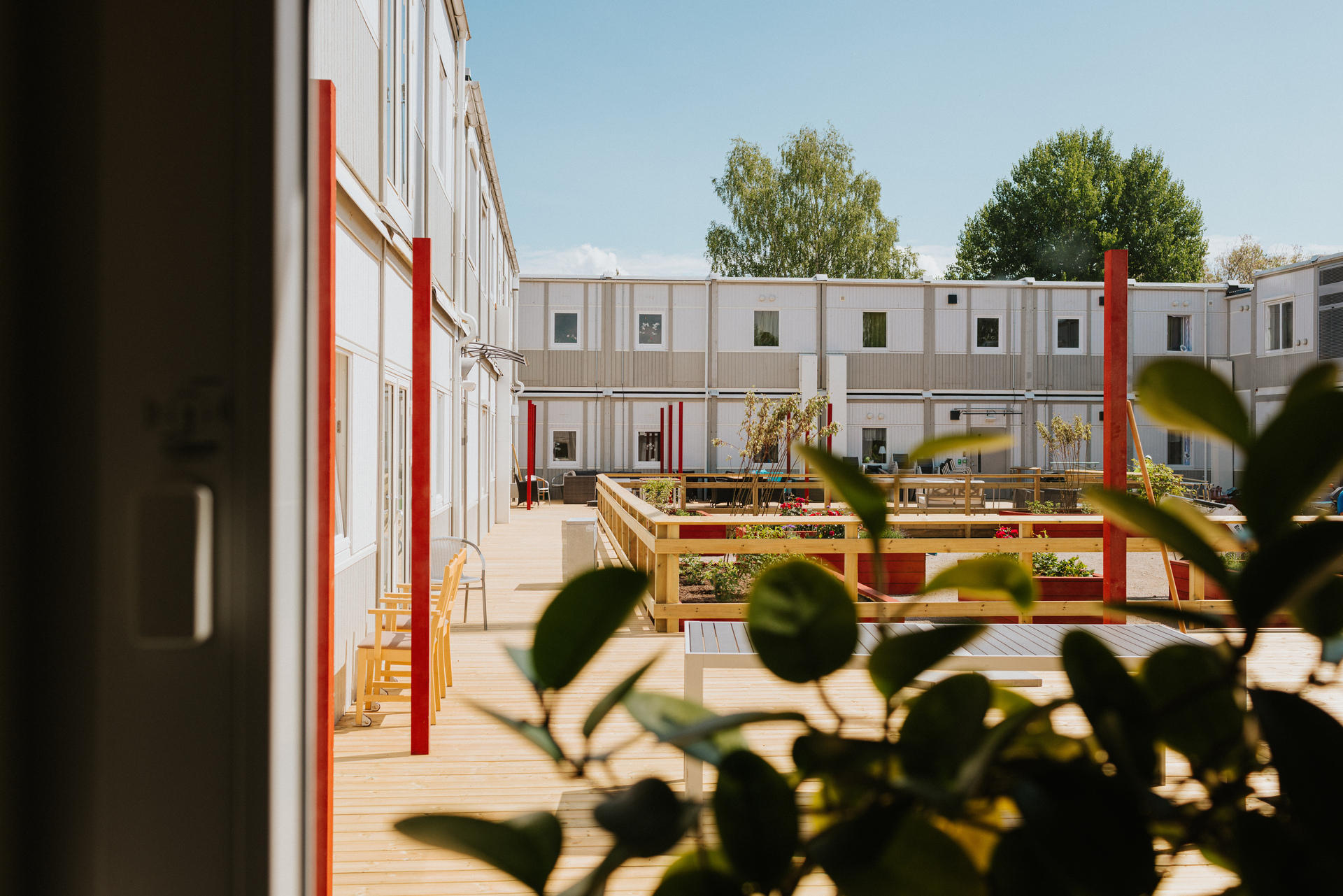 Innergård vid Herrhagsgården vård- och omsorgsboende i Falun med träbelagda gångar, planteringar och utemöbler. Moduler i två plan omger gården och skapar en lugn och trivsam utemiljö.