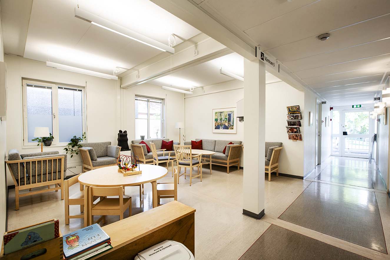 Väntrum i vårdcentral uppförd med moduler från Expandia, med soffor, runda bord och ljus korridor intill.