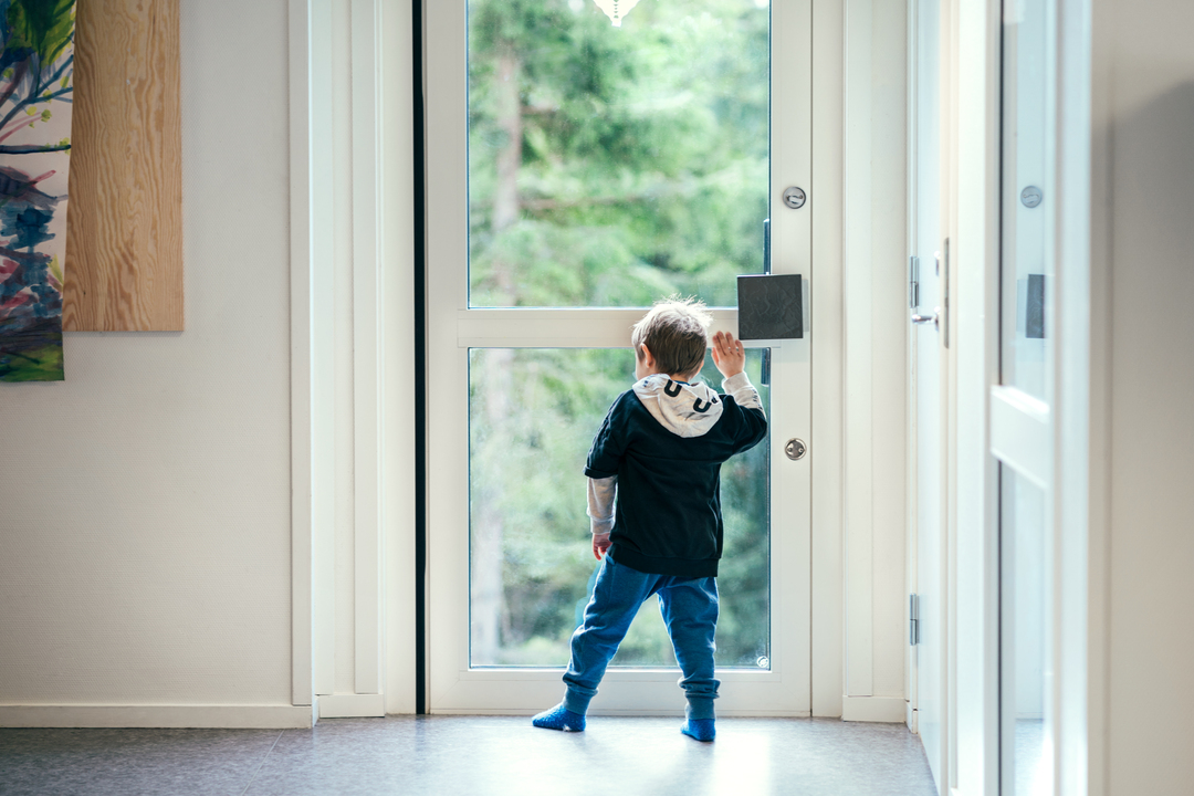 Barn som står ved døren og ser ut i naturen fra et lyst barnehagerom i modulbygg fra Expandia.