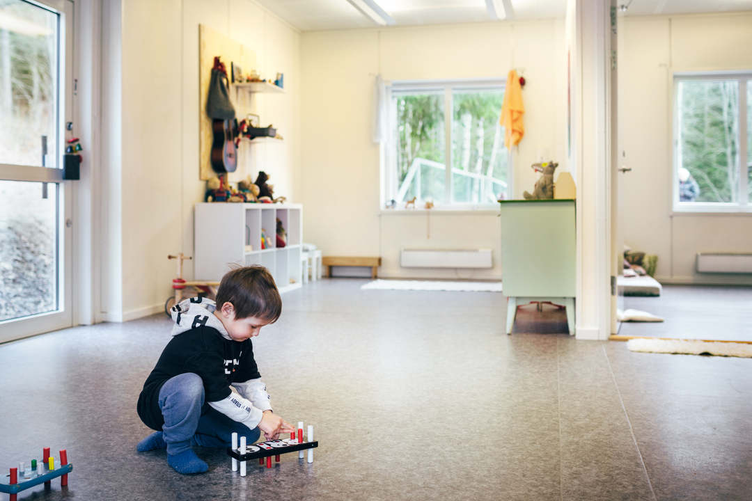 Barn som leker på gulvet i et lyst og romslig barnehagerom i modulbygg fra Expandia, med god plass til lek og utforskning.