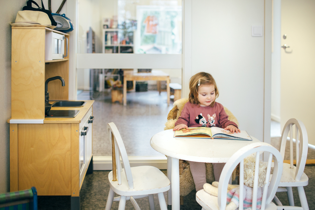 Barn som sitter og leser ved et lite bord i et lyst og hjemmekoselig barnehagemiljø med modulbygg fra Expandia.