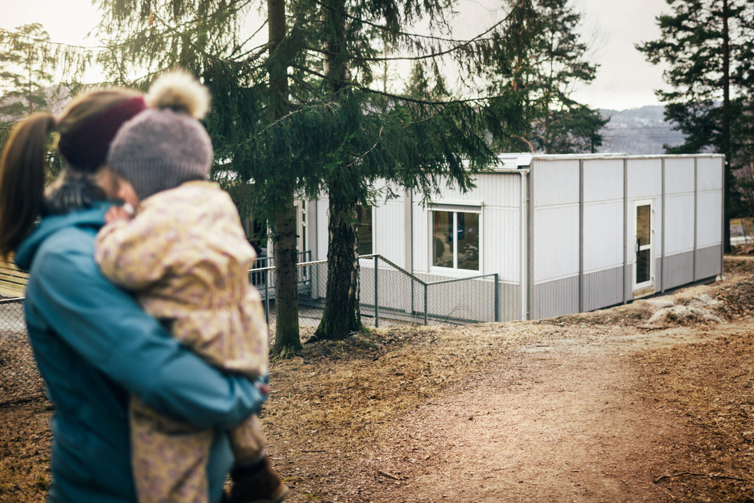 Barn og voksen på tur utenfor Sturlahuset barnehage i Drammen, med modulbygg fra Expandia i naturskjønne omgivelser.
